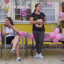 Tjejer sitter på en altan. Det är kalas med rosa ballonger, fika och en liten hund