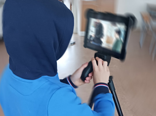 Ett barn med huva filmar med en iPad på stativ