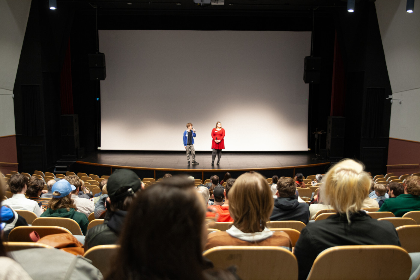 Två personer på stor scen framför publik. 