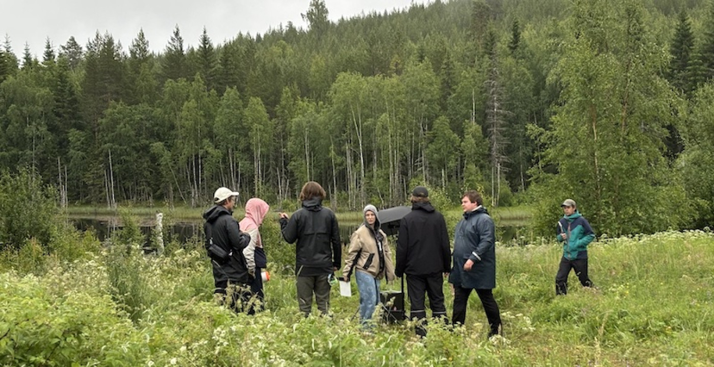 filmteam på en äng framför en tjärn i renget